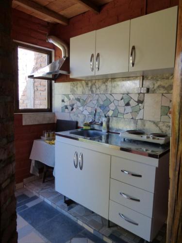 a kitchen with white cabinets and a sink at Cabaña Taski Wasi in Santa María