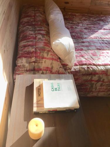 a book and a candle on a table next to a bed at Cabañas Isla San Jose in Tigre