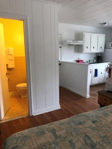 a kitchen with white cabinets and a toilet in a room at Swell Motel in Buxton