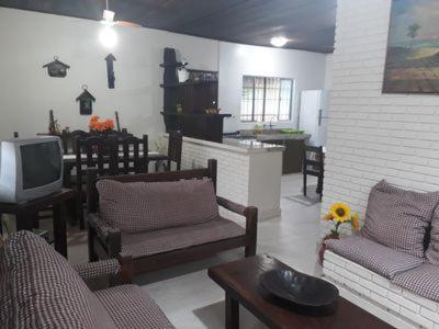 - un salon avec des chaises, une télévision et une table dans l'établissement CASA ESPAÇOSA 4 DORMITÓRIOS A 150M DA PRAIA DA MARANDUBA / UBATUBA, à Ubatuba