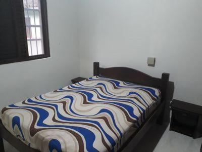 een bed met een kleurrijke deken erop in een kamer bij CASA ESPAÇOSA 4 DORMITÓRIOS A 150M DA PRAIA DA MARANDUBA / UBATUBA in Ubatuba