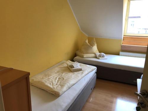 Cette petite chambre comprend 2 lits et une fenêtre. dans l'établissement Zweibettzimmer, à Kaiserslautern