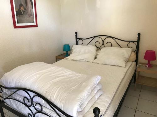 uma cama com lençóis brancos e almofadas num quarto em Goelands em Palavas-les-Flots