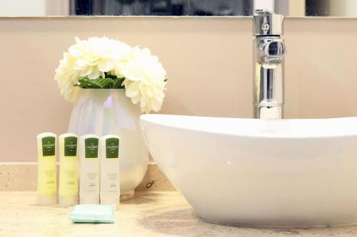 a bathroom with a sink and a vase with white flowers at Premier apartment in the heart of Mexico 802 in Mexico City