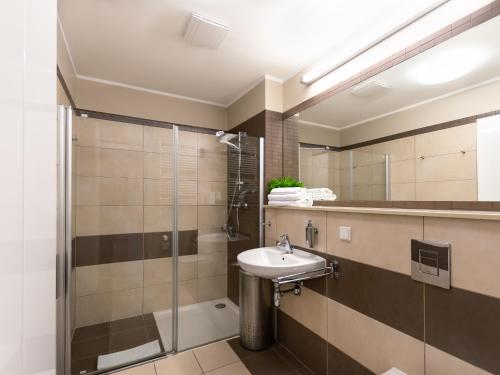 ein Bad mit einem Waschbecken und einer Dusche in der Unterkunft VacationClub – Olympic Park Apartament B8 in Kołobrzeg