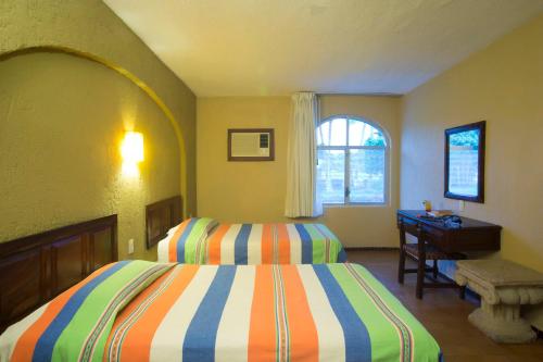 a bedroom with two beds and a desk and a window at Vista Vallarta All Suites On The Beach in Bucerías