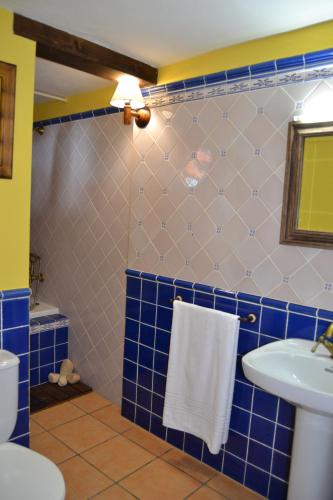 a blue tiled bathroom with a sink and a toilet at Casa Gorreta in Guinea