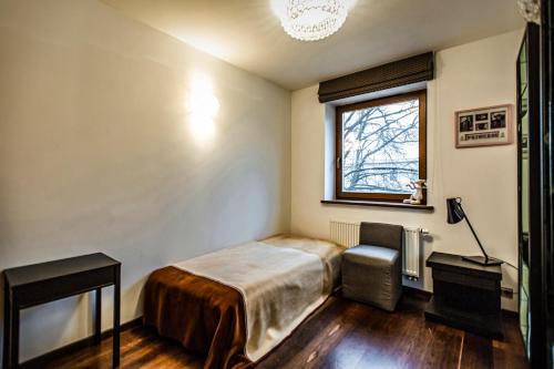 a bedroom with a bed and a chair and a window at Apartment with a Terrace over the Old Town Two Bedrooms in Kaunas