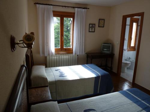 a bedroom with two beds and a window at Apartahotel Faure in Sallent de Gállego