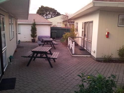 a patio with three picnic tables and a house at Motel 22 in Lower Hutt