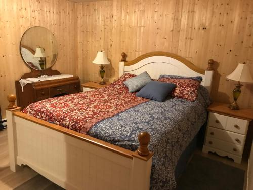 1 dormitorio con cama y espejo en Le Gîte du Pêcheur, en Metabetchouan