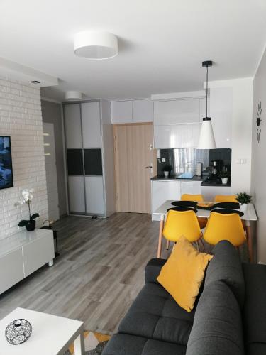 a living room with a gray couch and yellow pillows at Apartament Mateusz in Świnoujście