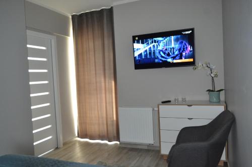 a room with a tv on a wall with a dresser at Apartament Mateusz in Świnoujście