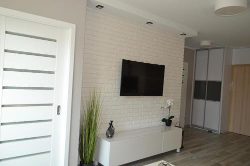 a living room with a tv on a white brick wall at Apartament Mateusz in Świnoujście