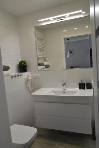 a white bathroom with a sink and a mirror at Apartament Mateusz in Świnoujście