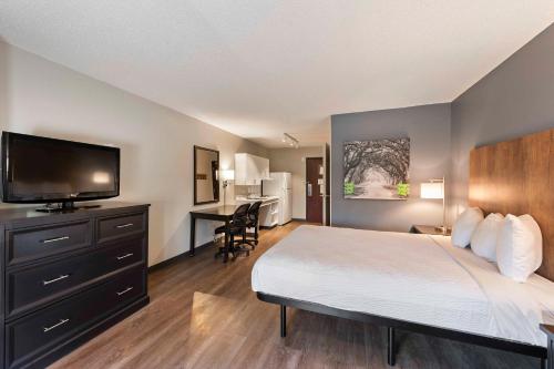 a hotel room with a bed and a flat screen tv at Extended Stay America Suites - Charlotte - University Place in Charlotte