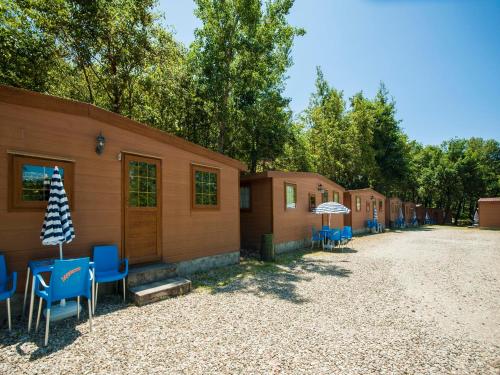 a row of houses with blue chairs and an umbrella at Camping Village Mugello Verde in San Piero a Sieve