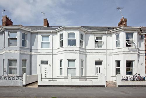 a white house with a white fence in front of it at Sunnymead Penthouse - Close to beach, Pets welcome, Balcony in Exmouth