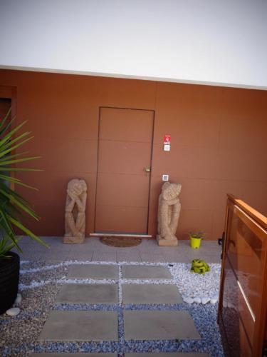 Habitación con 2 estatuas de piedra junto a una pared en Suites da Ria, en Mexilhoeira Grande