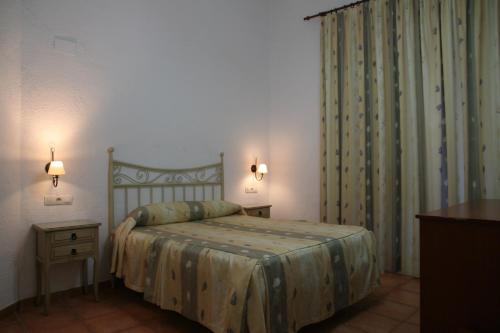 a bedroom with a bed and a dresser and curtains at Pensión San Joaquín in Granada