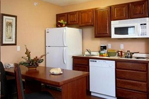 a kitchen with a white refrigerator and a wooden table at GrandStay Residential Suites Hotel Faribault in Faribault