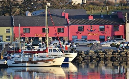 two boats docked in a marina with a red building at The Moorings Hotel & Seafood Restaurant in Portmagee