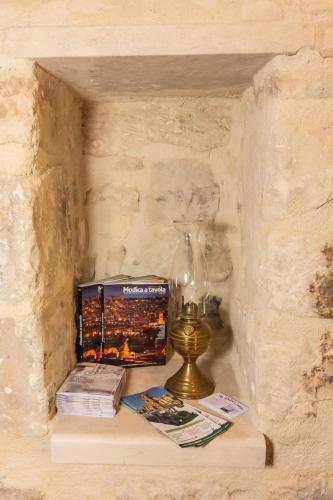 a lamp and books on a table in a stone wall at U Dammusu in Modica