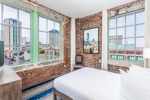una camera da letto con un muro di mattoni e due finestre di The Mercantile Hotel a New Orleans