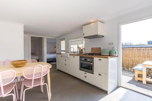 a kitchen with white cabinets and a table with chairs at George's Lodges Renesse in Renesse