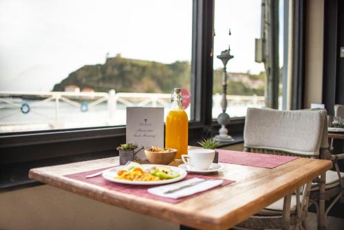 una mesa con un plato de comida y una botella de zumo de naranja en Hotel Villa Rosario II, Edificio Moderno, en Ribadesella