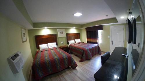 a hotel room with two beds and a couch at Travel Inn of Riviera Beach in Riviera Beach