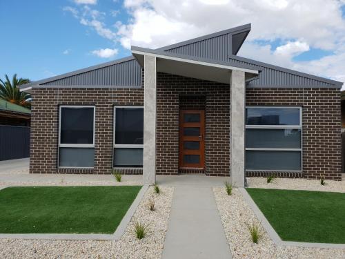 a brick house with a red door and grass at Wimmera Plains in Horsham