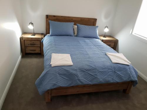 a bedroom with a bed with blue sheets and two lamps at Wimmera Plains in Horsham