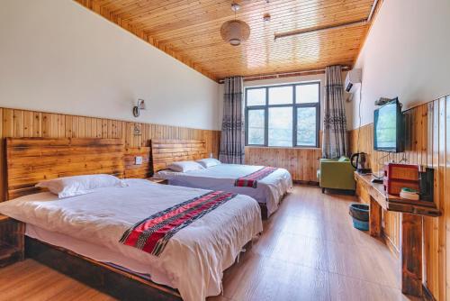 a bedroom with two beds and a flat screen tv at Mogan Guyue Guesthouse in Deqing