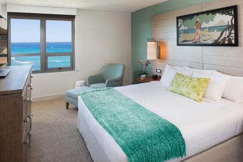a hotel room with a bed and a view of the ocean at Queen Kapiolani Hotel in Honolulu