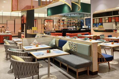 a restaurant with tables and chairs and a counter at ibis Styles Jakarta Tanah Abang in Jakarta