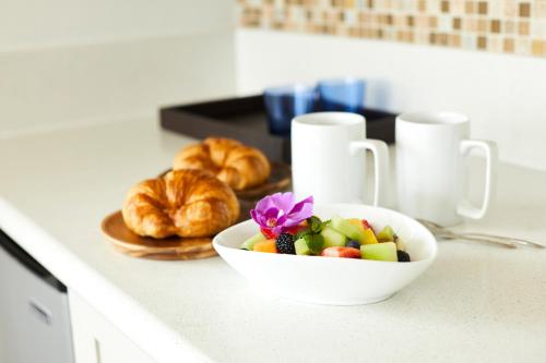 a bowl of fruit on a counter with a plate of croissants at Queen Kapiolani Hotel in Honolulu
