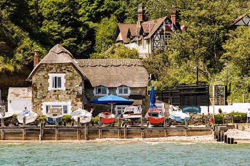 a house with boats parked outside of it next to the water at Cliff Top Apartment 3 Bedroom in Shanklin