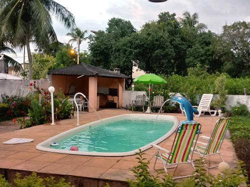 a swimming pool with two lawn chairs and a toy dolphin at Casa Ilha de Itaparica in Itaparica