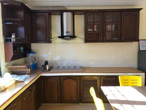 a kitchen with wooden cabinets and a table with yellow chairs at KERAI GUEST HOUSE TEMERLOH in Kampong Telok Mengkuang