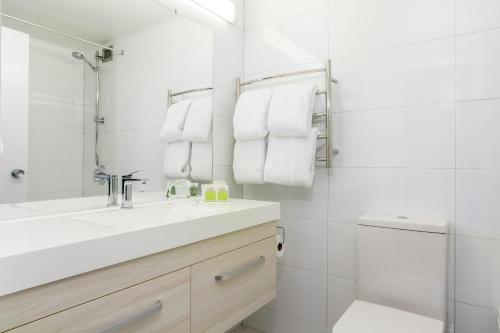 bagno bianco con lavandino e doccia di Heartland Ambassador Hotel Hamilton a Hamilton