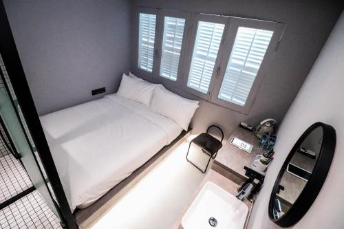 a small bedroom with a white bed and a sink at Rest Chinatown Hotel in Singapore