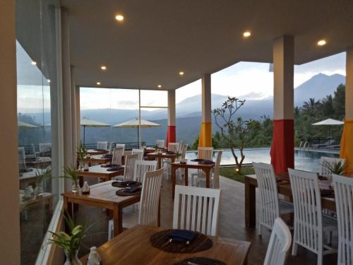 een restaurant met tafels en stoelen en uitzicht op de bergen bij Atres Sari Resort in Munduk