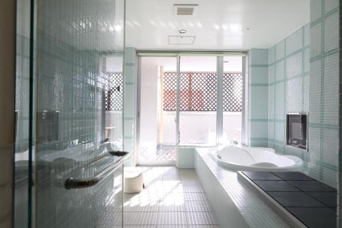 ein Bad mit einer Badewanne, einem Waschbecken und einem Fenster in der Unterkunft C-HOTEL affetto(Adult Only) in Sapporo