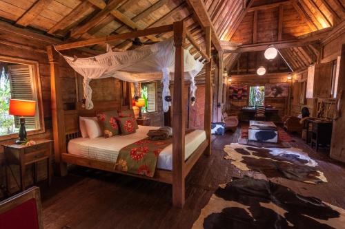 a bedroom with a canopy bed in a cabin at Ratua Private Island Resort in Aimbuei Bay