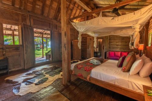 a bedroom with a bed in a log cabin at Ratua Private Island Resort in Aimbuei Bay