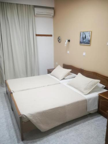 a bedroom with a large bed with white sheets at Hotel Dimitra Sun in Archangelos
