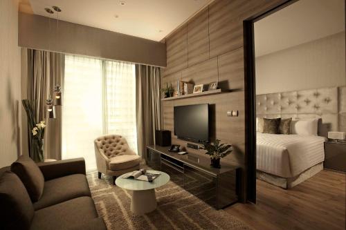 a hotel room with a bed and a couch and a television at Pan Pacific Serviced Suites Beach Road, Singapore in Singapore