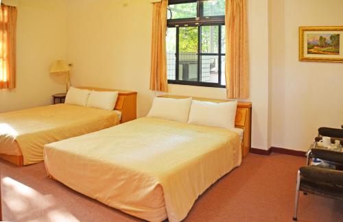 Habitación de hotel con 2 camas y ventana en Kaohsiung Meinong Rabbit Paul Homestay B&B, en Meinong
