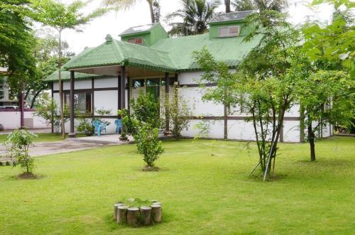 a house with a green roof and a yard with trees at Kaohsiung Meinong Rabbit Paul Homestay B&B in Meinong